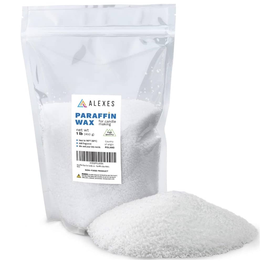 A clear plastic bag labeled "Alexes Paraffin Wax" is shown, containing white, granular wax perfect for crafting candles with dried flowers. The label indicates it's intended for candle making, with a net weight of 1 lb (454 g). A small heap spills out beside the bag, hinting at creative possibilities.